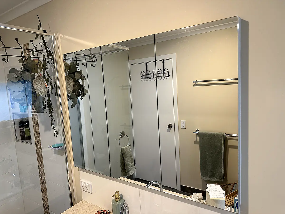 Bathroom mirror and shower glass cleaned, both surfaces reflecting sharply